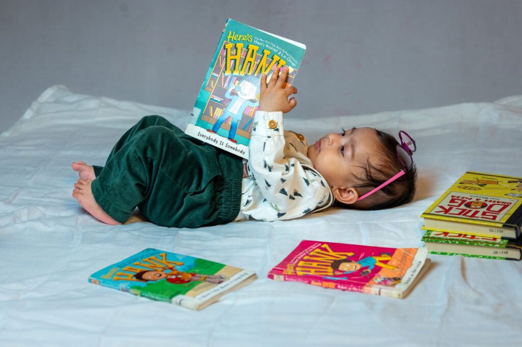 Baby lying on a bed surrounded by colorful board books