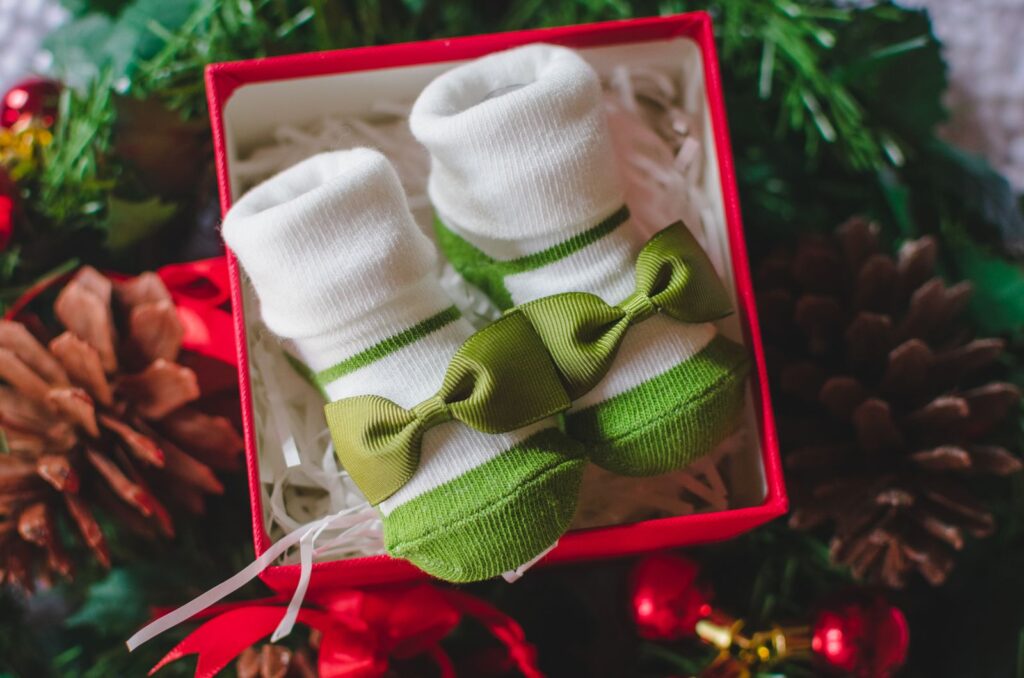 Pair of knitted baby booties in an open red gift box
