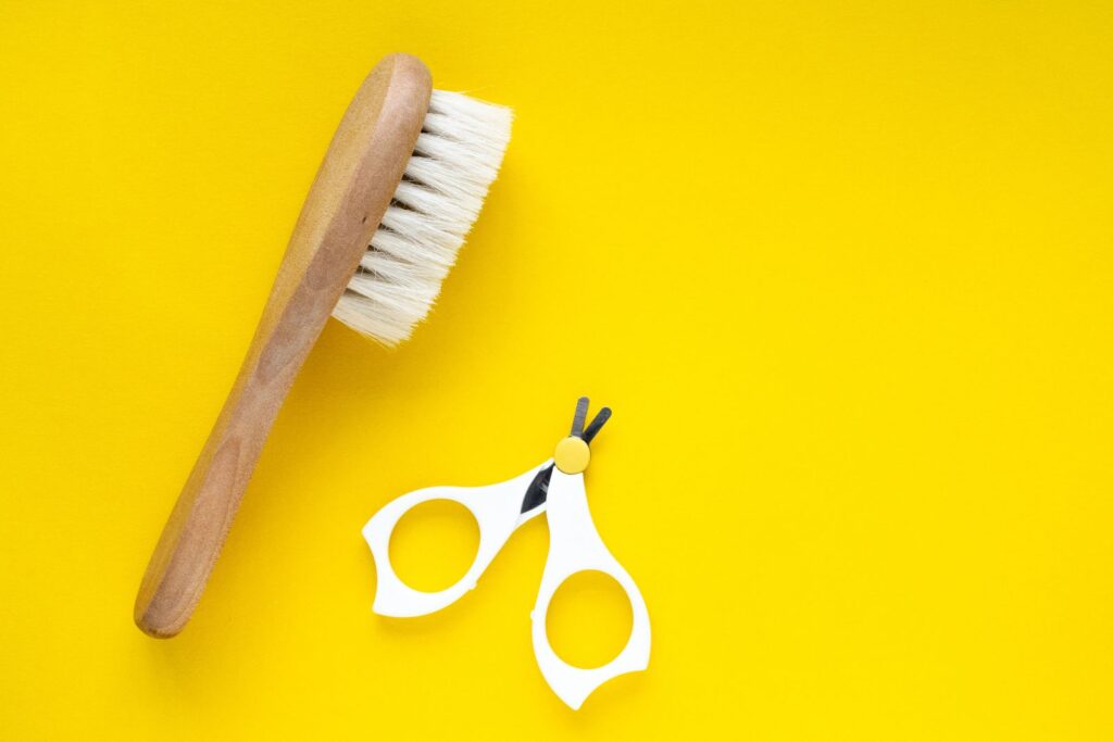 Wooden baby hairbrush and baby nail clippers on a yellow background