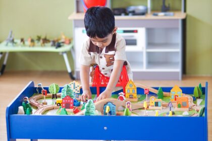 Boy playing at a colorful play table in a bright playroom with white shelves