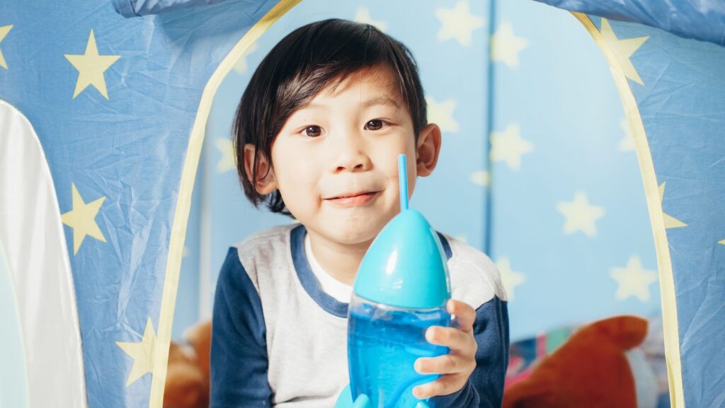 Young boy drinking from a blue kids' water bottle