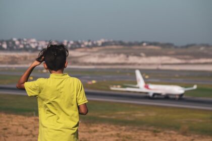Boy in a yellow T-shirt watching a plane on the runway