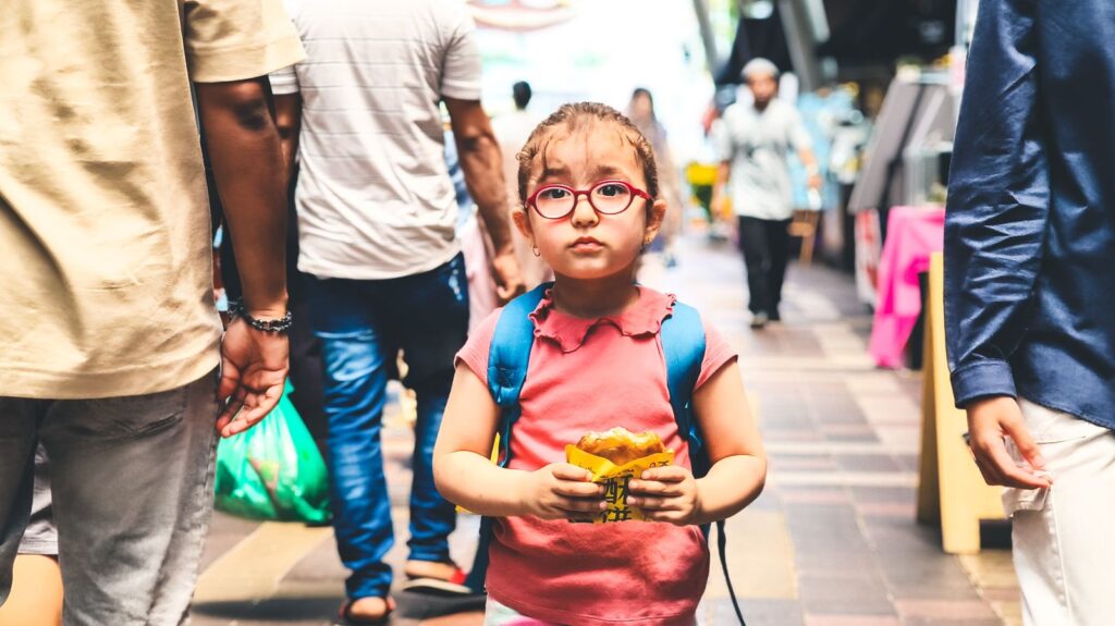 Young child with a backpack eating a snack while traveling