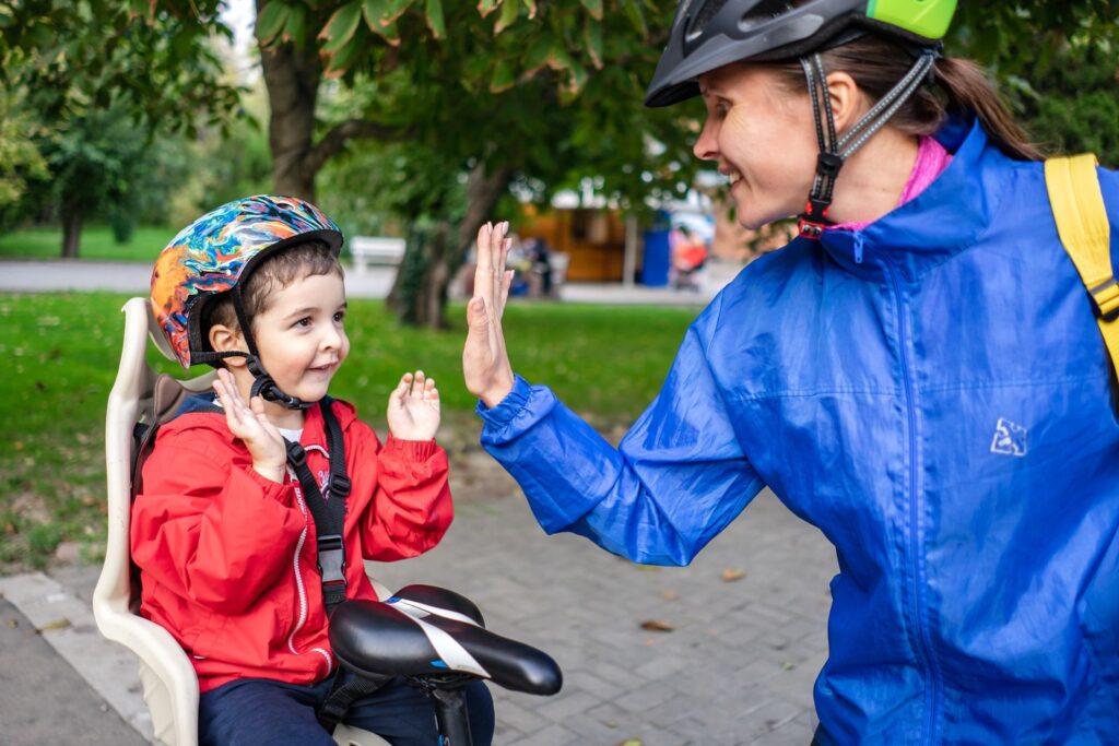 Child in a bike helmet giving a high five to a parent