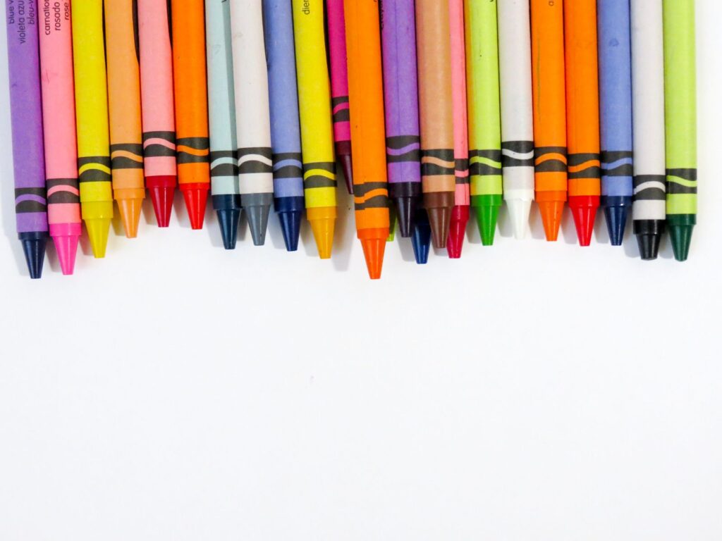 Row of colorful wax crayons on a white background