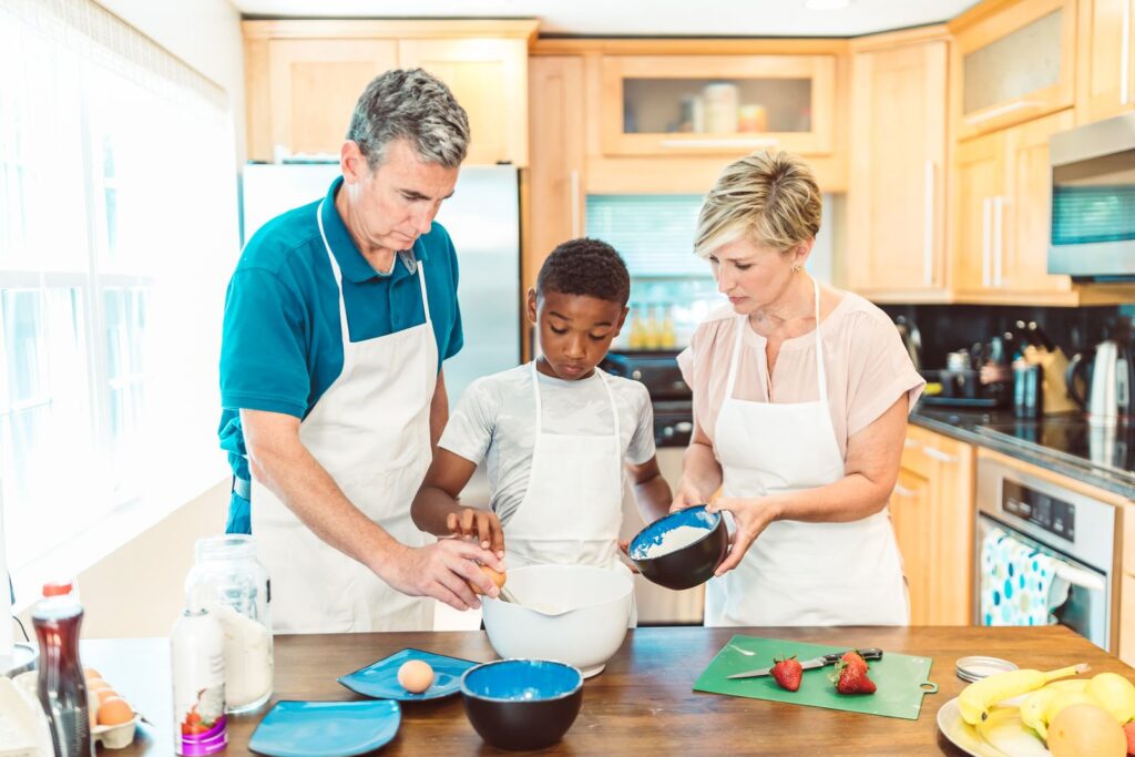 Parents and a boy in aprons cooking together in the kitchen