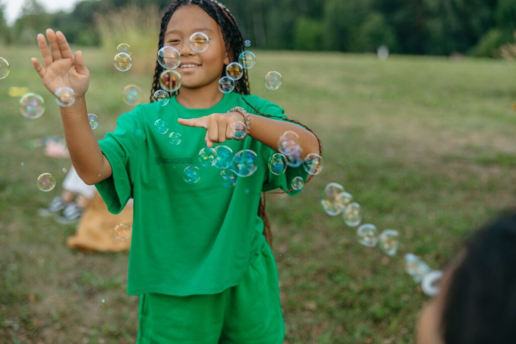 Girl in green blowing bubbles in a park
