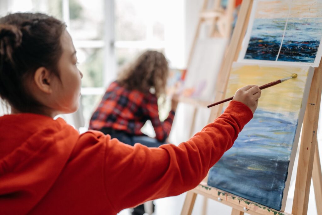 Girl painting a seascape on a canvas at an easel