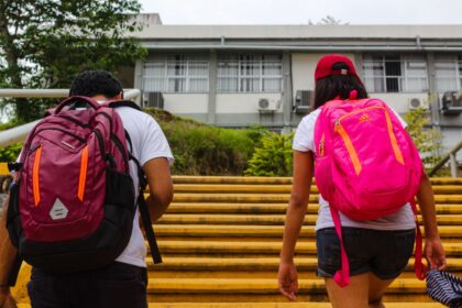 Children with bright pink backpacks walking up the steps to school
