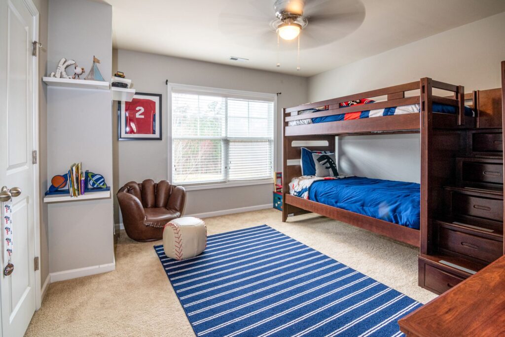 Kids' bedroom with a bunk bed, striped blue rug and window blinds