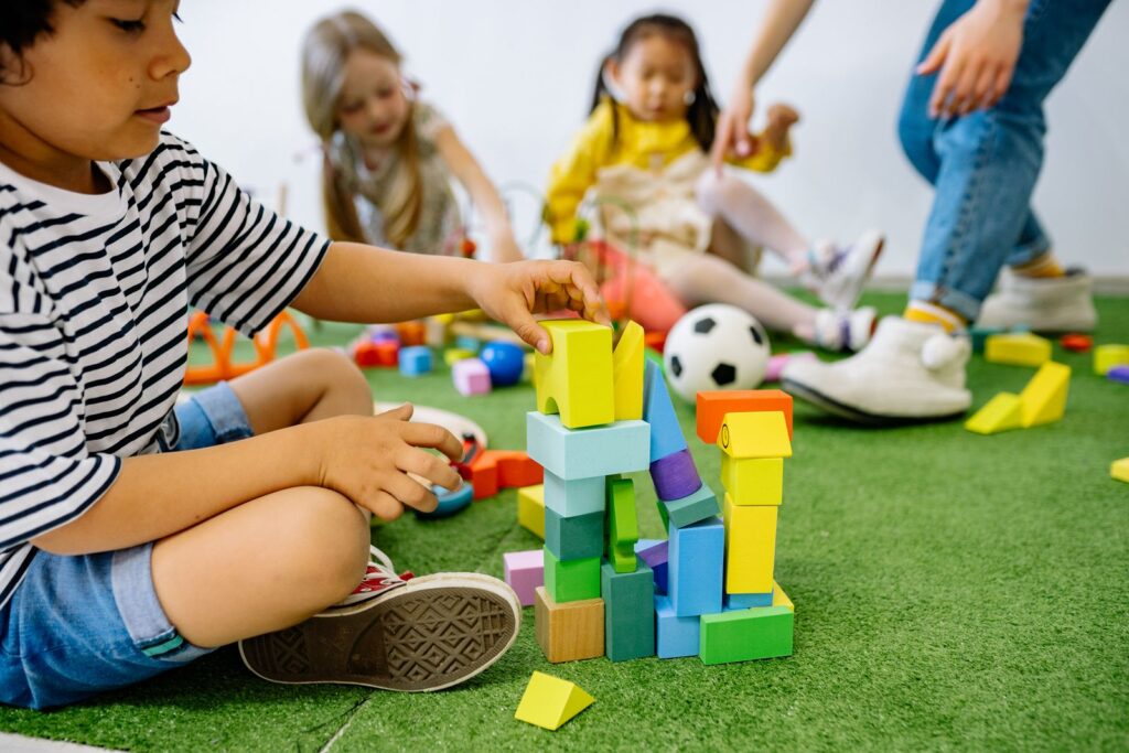 Children building with colorful blocks together on a grassy play mat