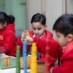 Children concentrating while building towers from colorful wooden blocks