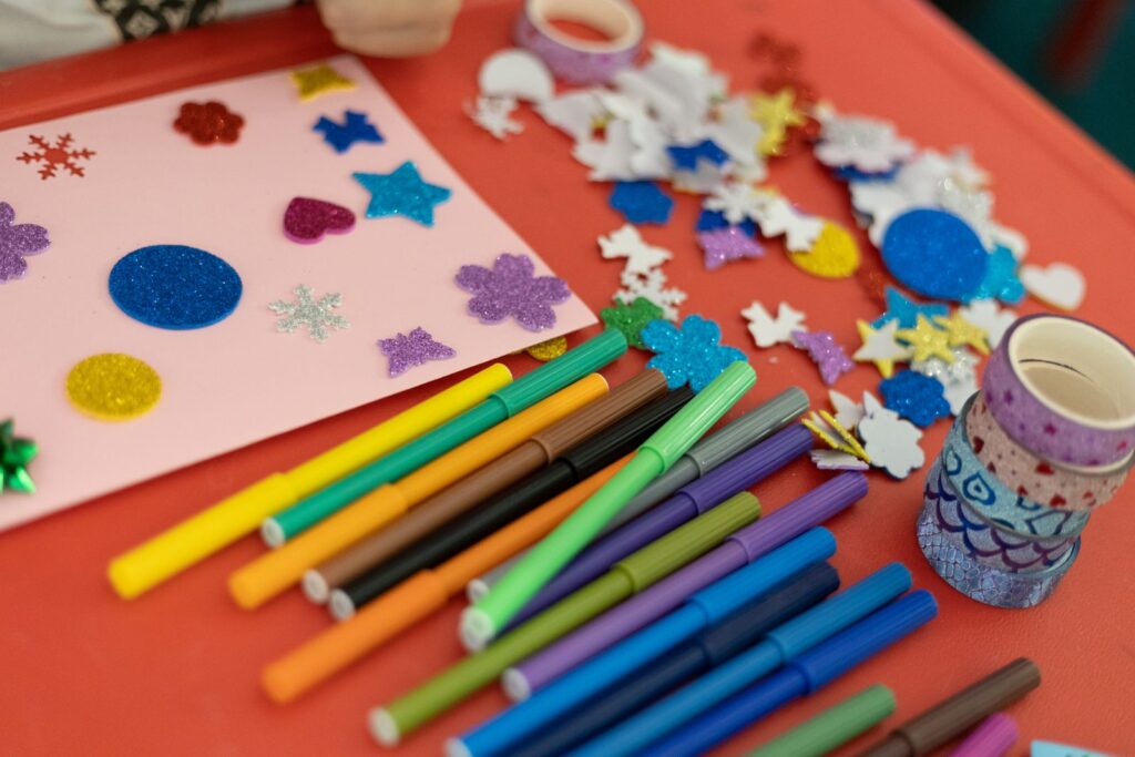 Markers, felt shapes and craft supplies spread across an orange table