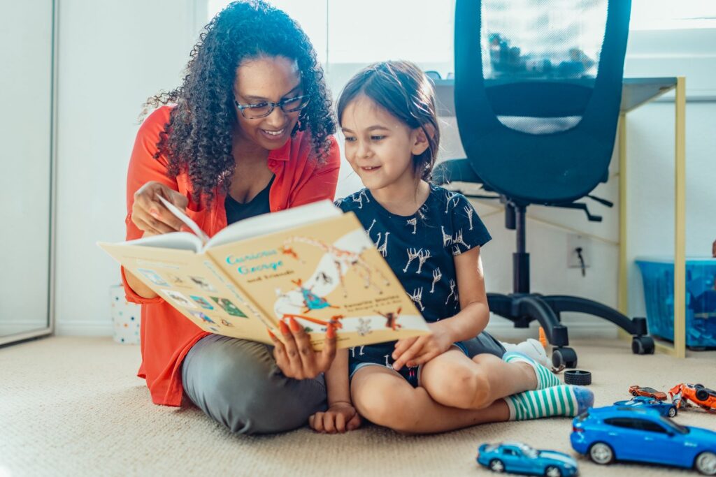 Mother and daughter sitting on the floor reading a picture book