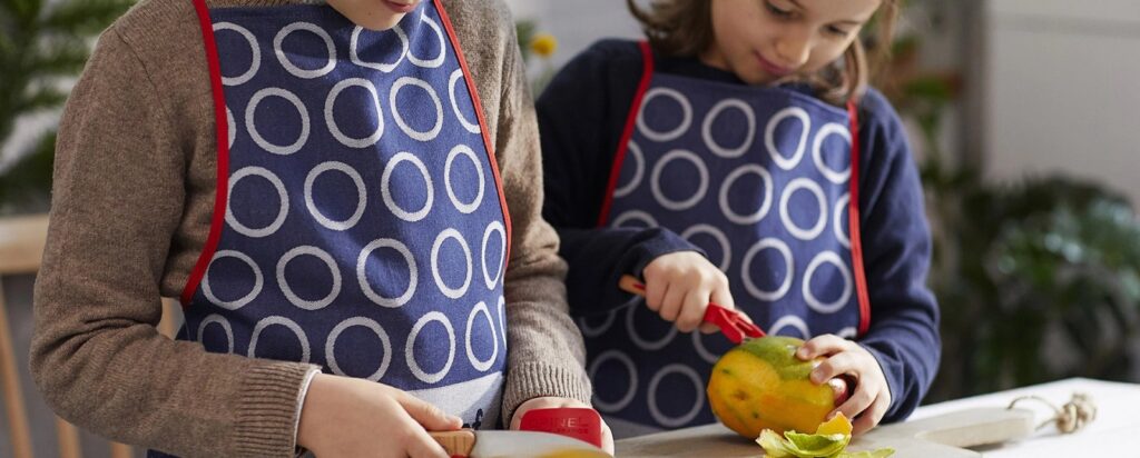 Two children in aprons cutting fruit with Opinel Le Petit Chef knives