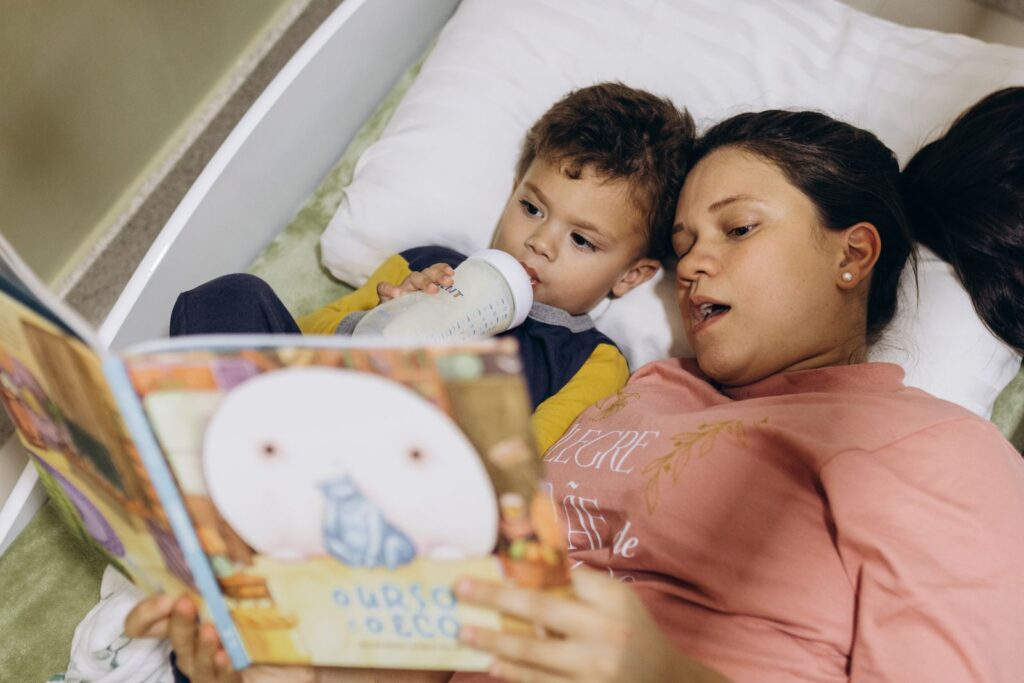 Parent and child lying in bed reading a picture book together