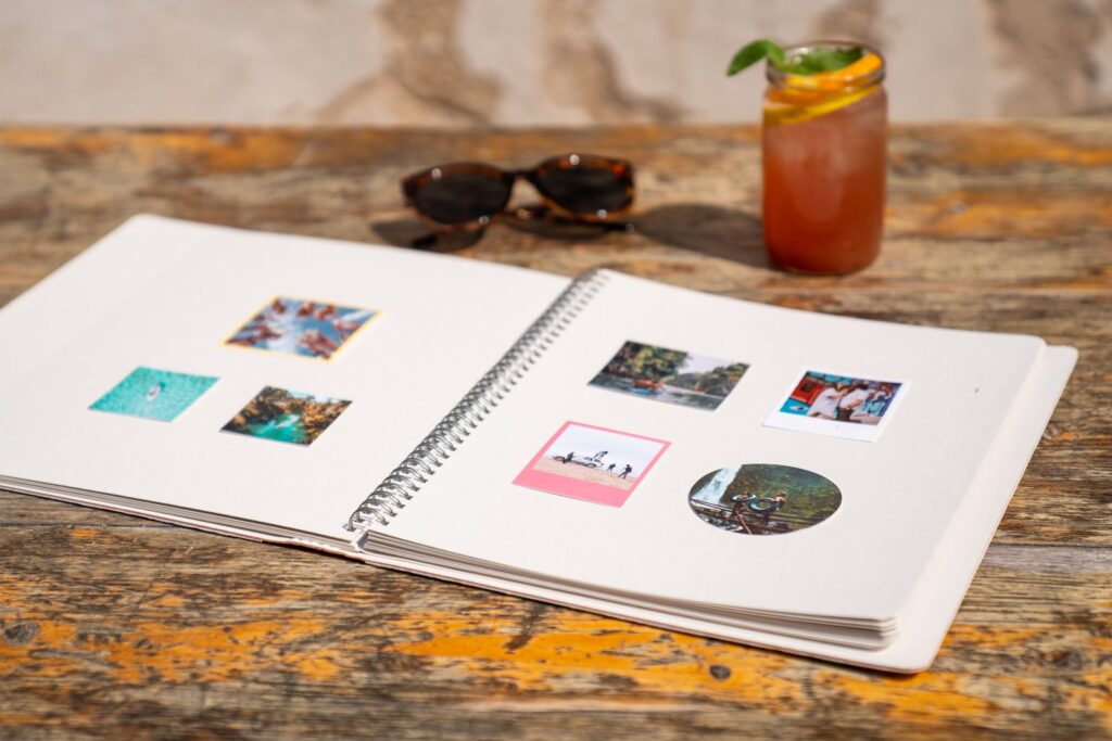 Open photo album with snapshots on a wooden table