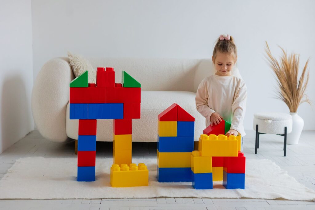 Toddler building a colorful block house on a rug