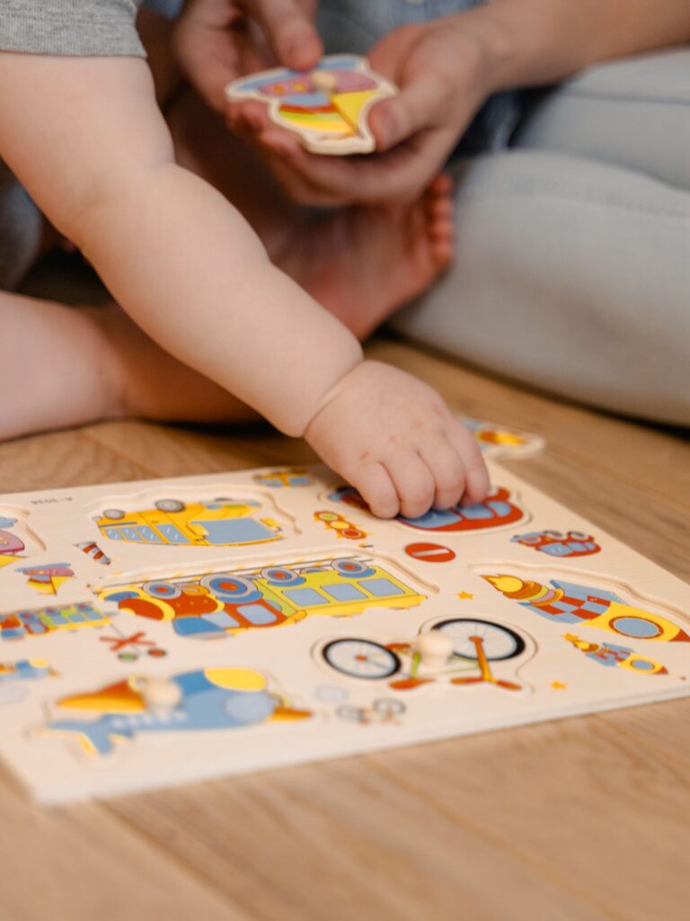Toddler's hand reaching for a piece of a colorful wooden knob puzzle