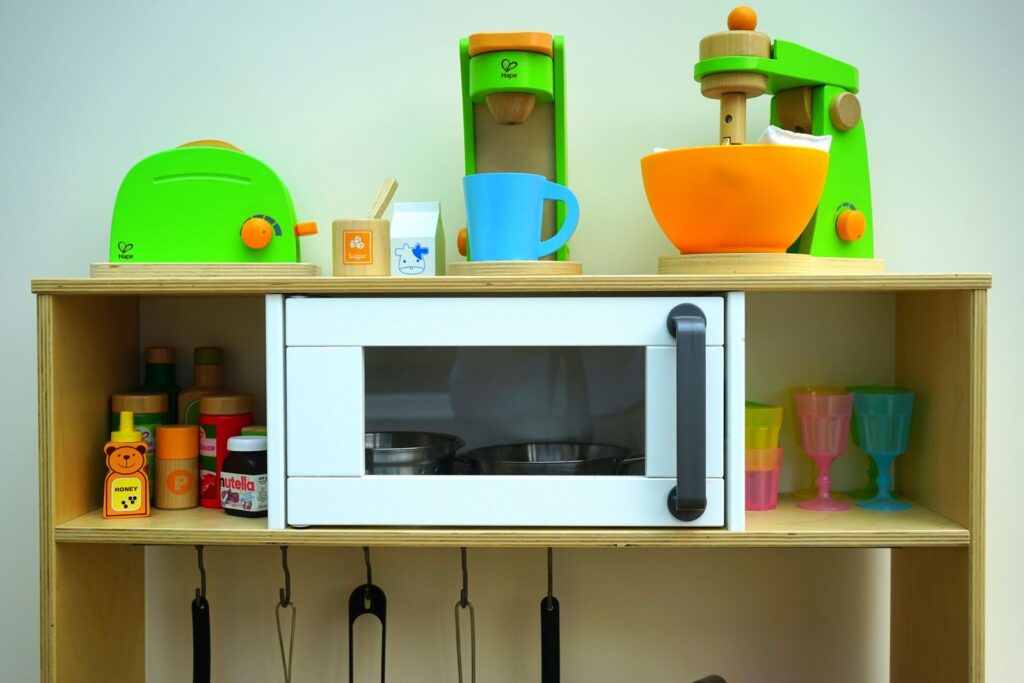 Wooden play kitchen with a toy microwave, toaster and mixer