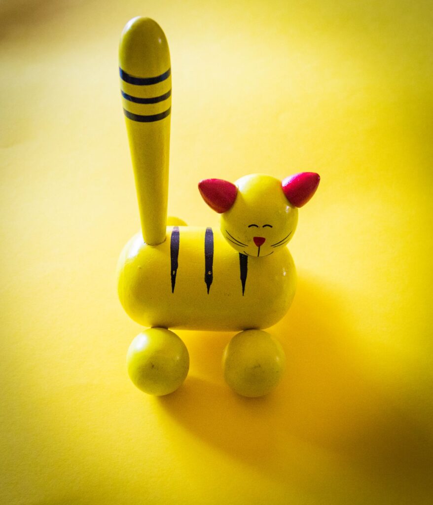 Bright yellow wooden cat toy on round wooden wheels